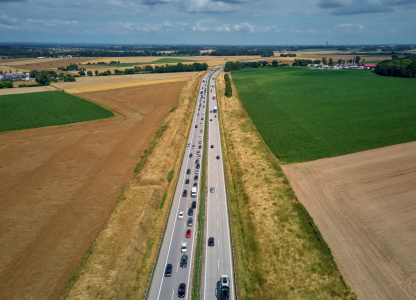 Aerial view of highway traffic with freight trucks and cars in motion. Concept of commercial transportation, delivery logistics and road infrastructure