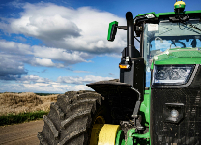 John Deere 8R 410 tractor with grain cart on a harvested field in Ukraine on August 7, 2023